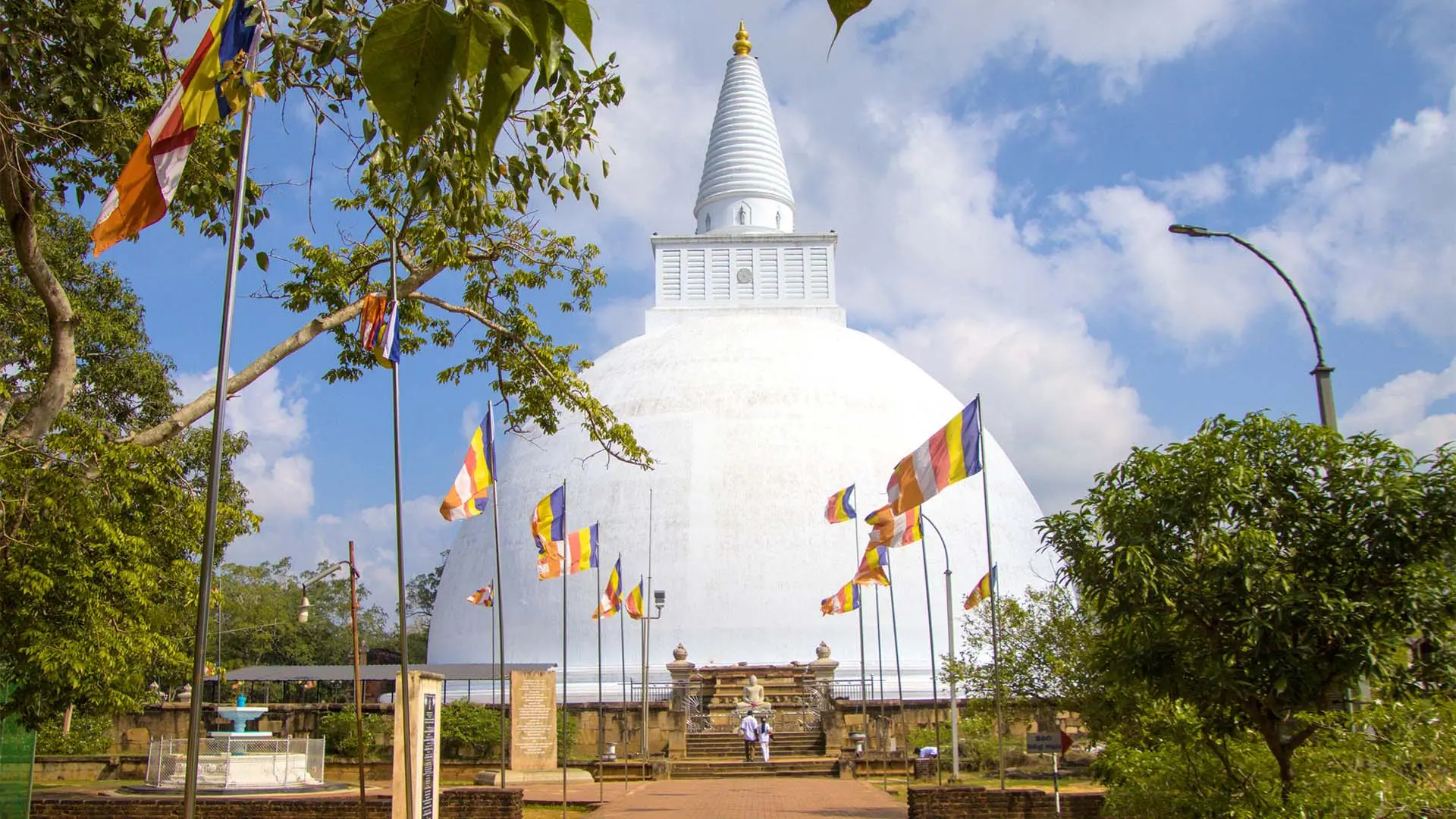 Mirisawetiya stupa with golden spire amidst lush greenery under a clear blue sky.