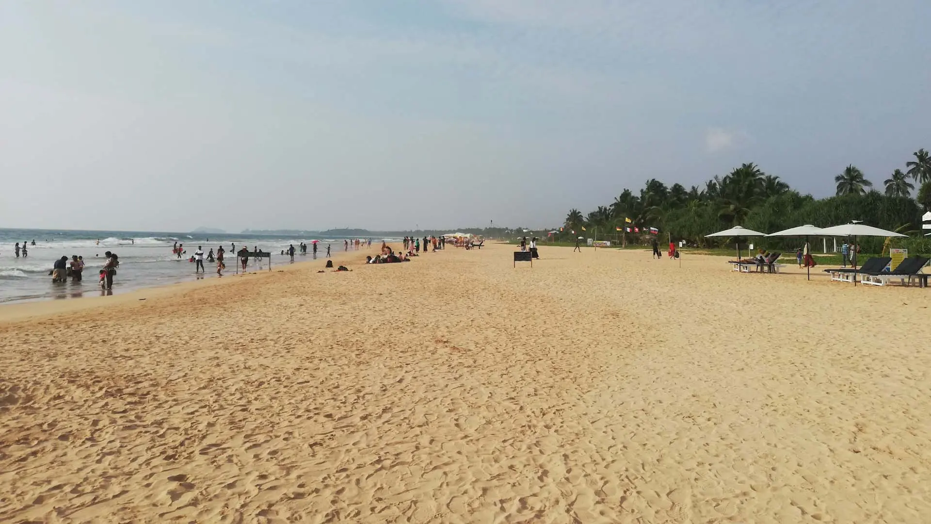 Bentota Beach with serene sandy shoreline and lush greenery under a partly cloudy sky.