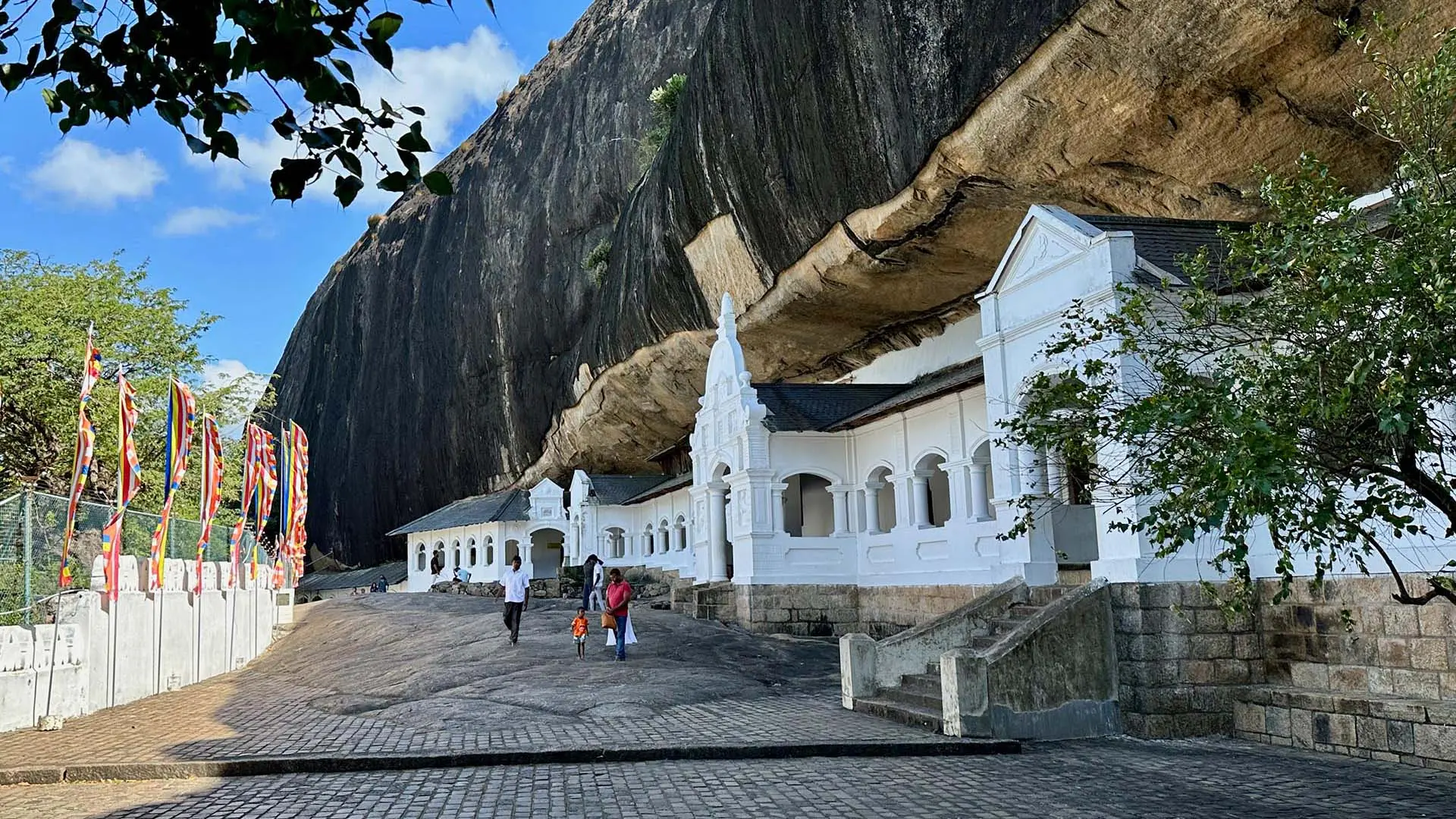 Dambulla Royal Cave Temple with white structures under a rock overhang.