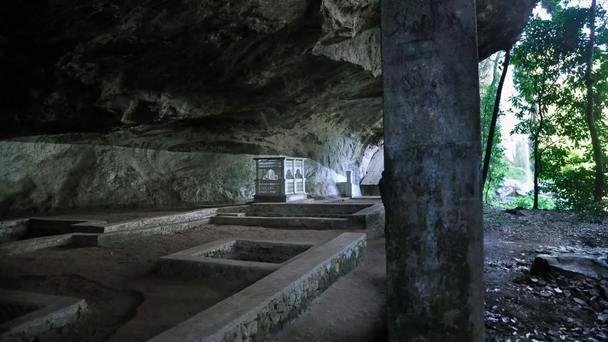 Interior of Kitulgala Belilena Cave with ancient stone structures and a small shrine.