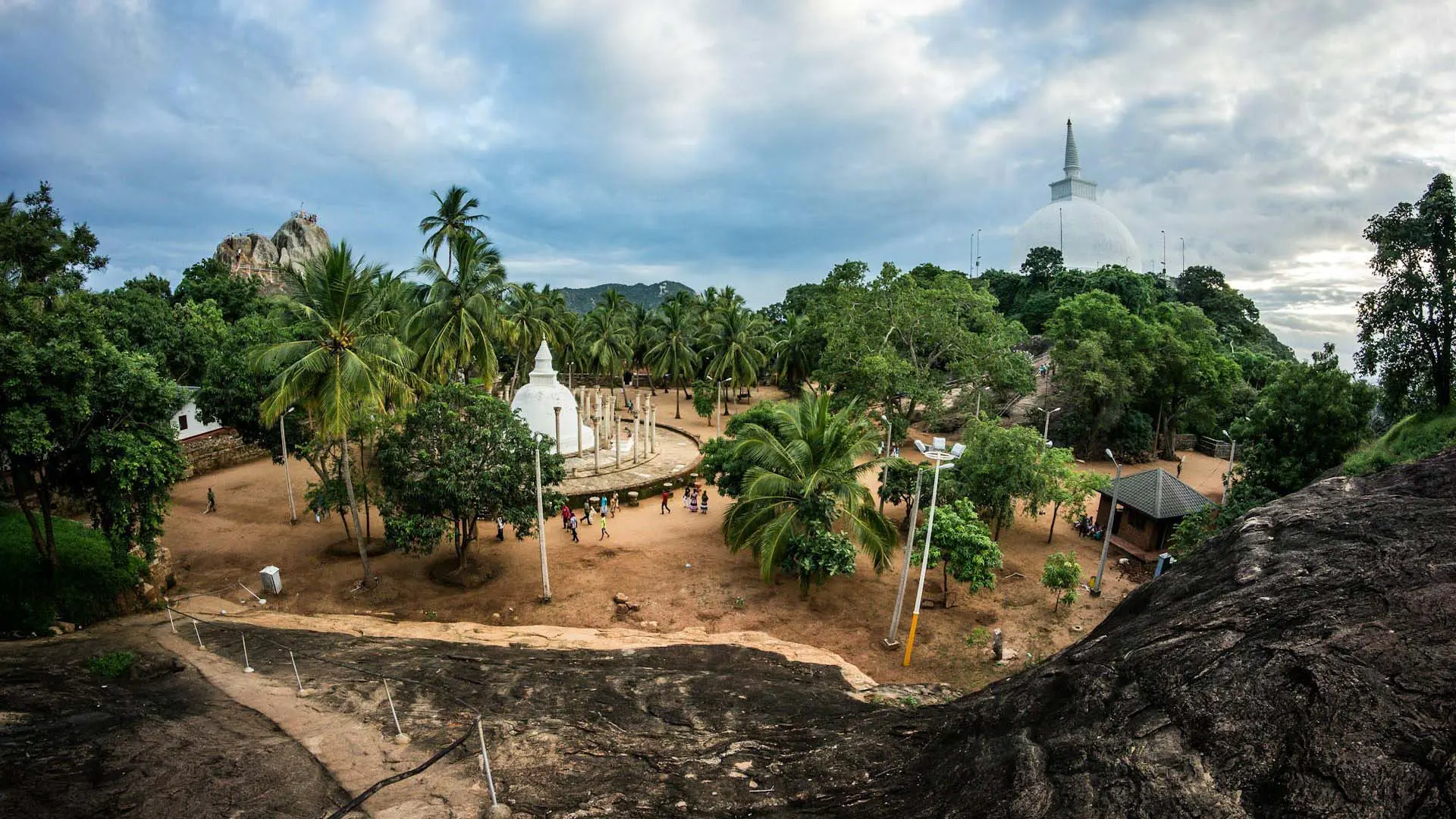 Mihintale surrounded by lush greenery under a cloudy sky.