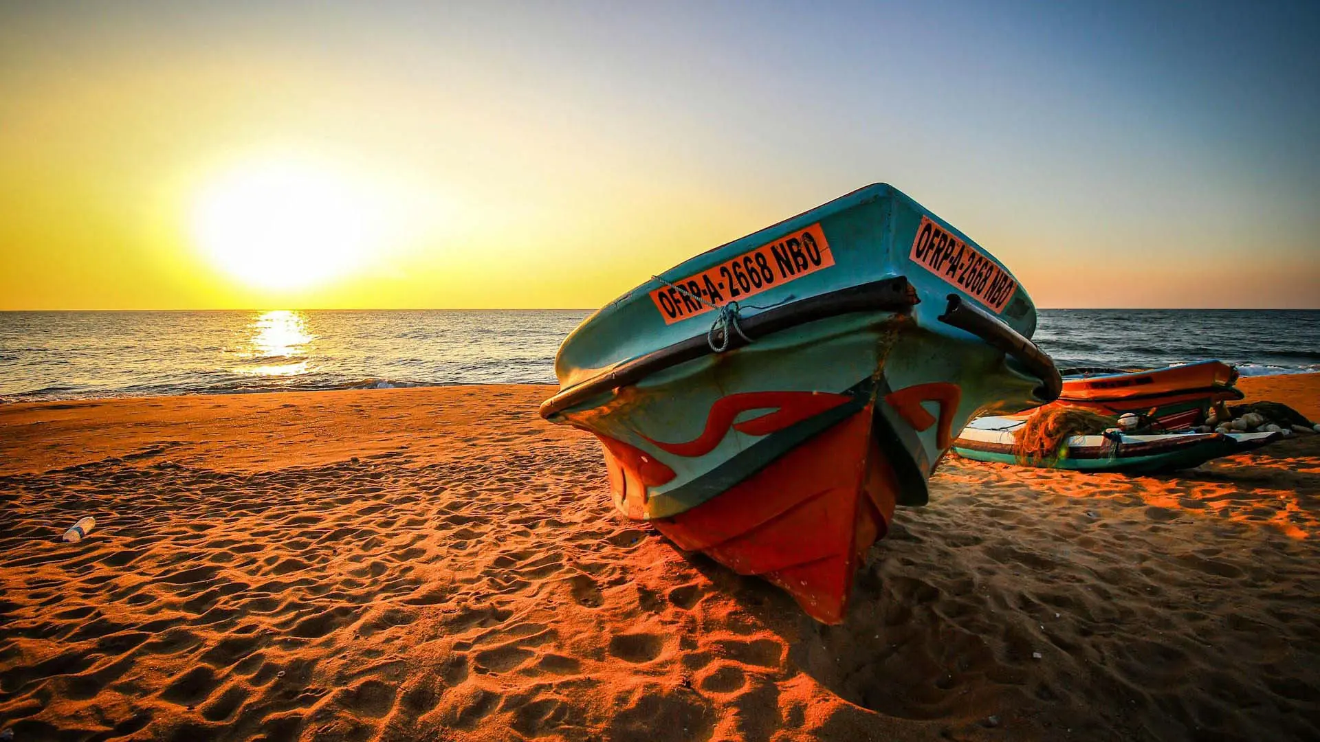 Colorful fishing boat on Negombo Beach at sunset, with golden sand and serene ocean views.