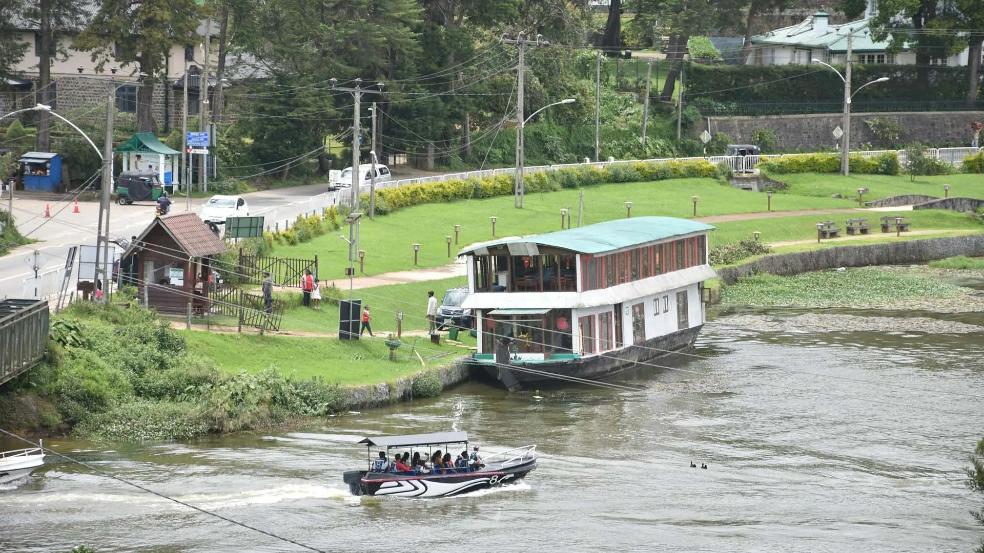Boat tour with a houseboat and speedboat on the water in Nuwara Eliya’s green landscapes.